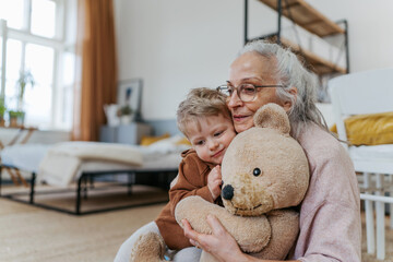 Wall Mural - Grandmother cuddling her little grandson with bear toy.