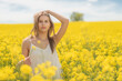 Beautiful woman with long blonde hair. He walks in the rapeseed field