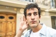 © Asier - Young handsome caucasian man at outdoor trying to listening a gossip.