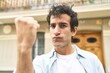 © Asier - Young handsome caucasian man at outdoor showing fist to camera, aggressive facial expression.