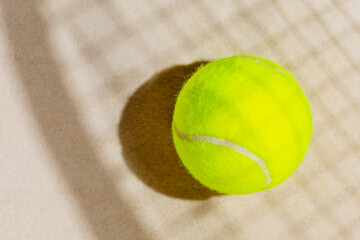 Wall Mural - Tennis yellow ball on the sand beach with racket shadow. Tennis competitions, healthy sport and outdoor activities concept. Flat lay