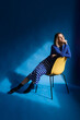 © Tania Cervian/Stocksy - Relaxed woman sitting on chair against blue background