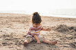 © Katherine Monge/Stocksy - Toddler Girl Sitting and Playing At The Beach