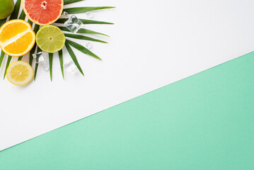 Wall Mural - Fruity floral arrangement concept. Top view of refreshing orange, grapefruit, and lime slices on white teal background with copy space for text or advert