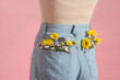 © Marc Tran/Stocksy - Woman with beautiful tender flowers in back pocket of jeans