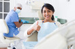 © JackF - Smiling hispanic female patient showing thumb up after procedures in modern dental clinic
