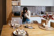 © Manu Padilla/Stocksy - Woman photographing table setting in kitchen