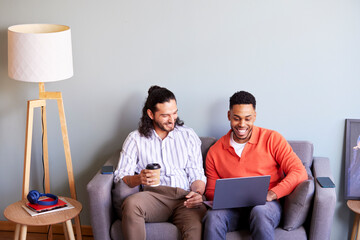 Glad diverse men sitting with laptop in workplace