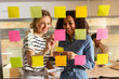 © BONNINSTUDIO/Stocksy - Business professionals brainstorming using adhesive notes in office