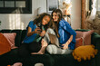 © Léa Jones/Stocksy - smiling friends taking a selfie on sofa
