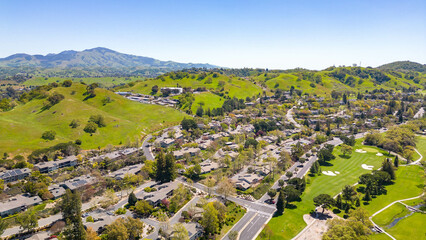 Wall Mural - A stunning drone photo captures the Rossmoor community's picturesque beauty, showcasing homes, a golf course, green hills, and a clear blue sky.