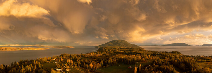 Wall Mural - Beautiful Island Sunset With Dramatic Storm Clouds Across the Salish Sea Area of the Pacific Northwest. Aerial panoramic view of Lummi Island, Washington just after a spring rain shower.