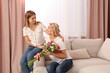© New Africa - Young daughter congratulating her mom with flowers at home. Happy Mother's Day