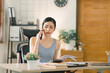 © PRIME STOCK LAB - The millennial Asian young businesswoman adviser is analyzing and discussing the financial report situation on cellphone in her home office, financial, accounting, and investment advisor concepts.