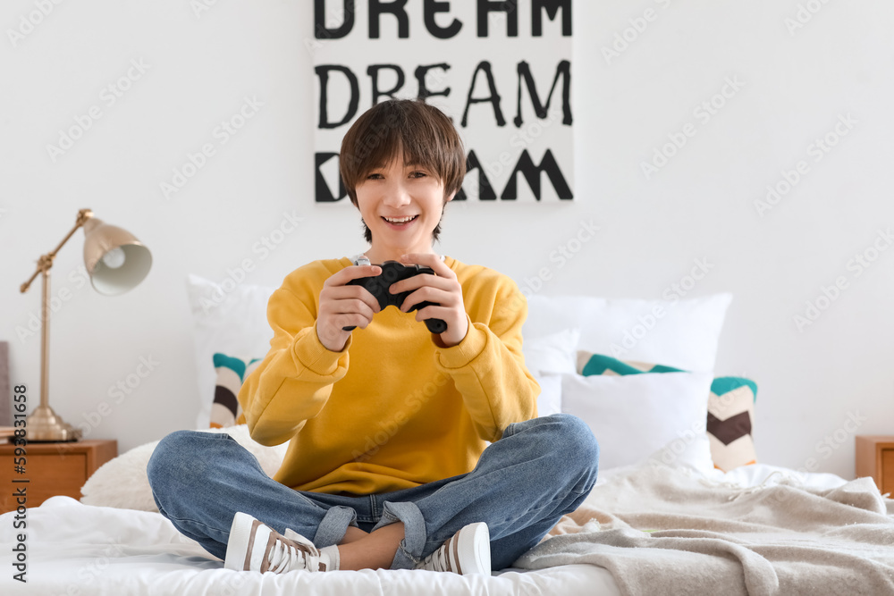 Teenage boy playing video game in bedroom