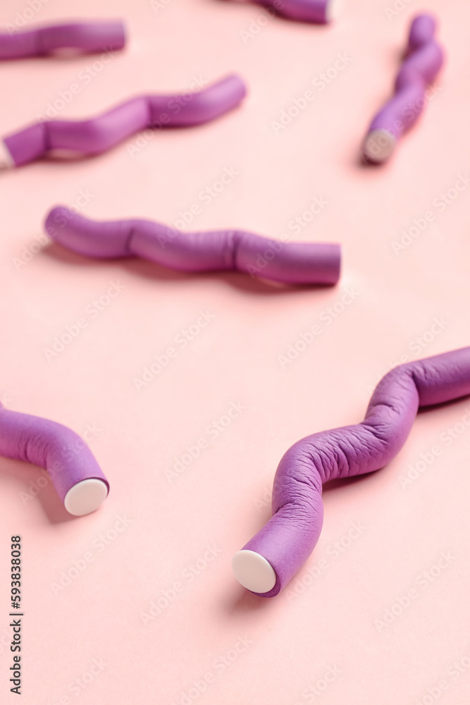 Hair curlers on pink background, closeup
