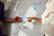 © DragonImages - Hands of business people pointing at chart on whiteboard discussing website visiting activity