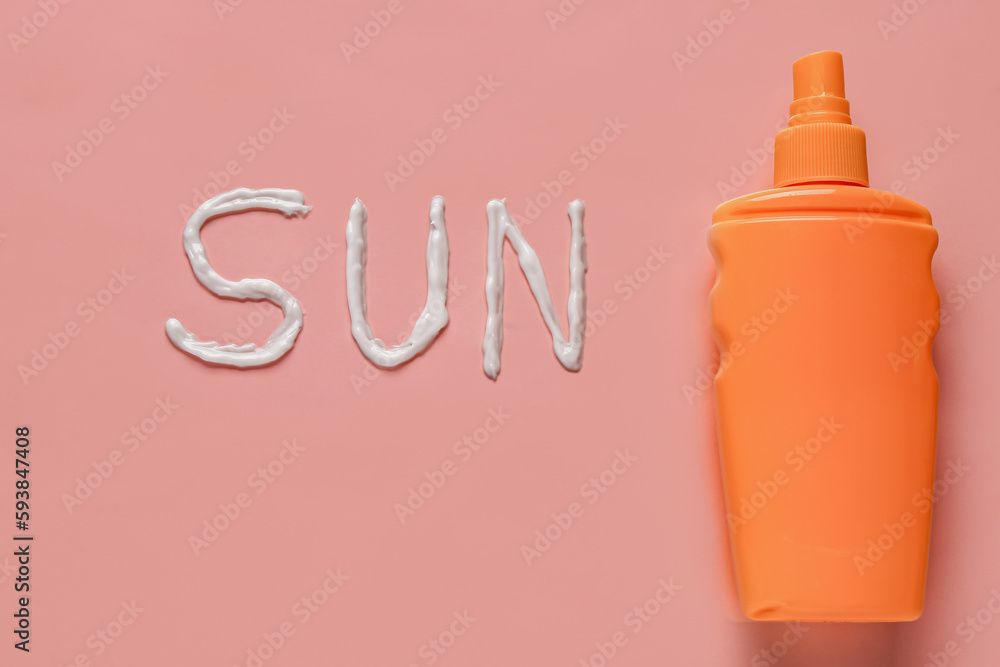 Word SUN made of sunscreen cream on pink background