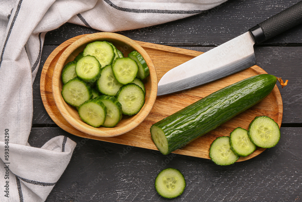 Bowl with fresh cut cucumber on dark wooden background
