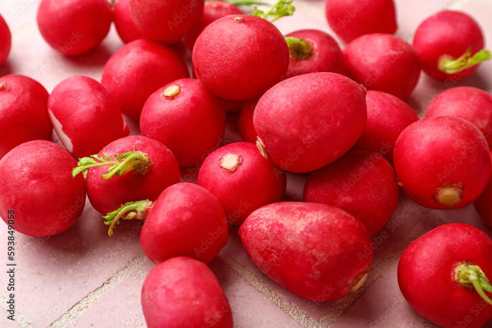 Heap of fresh radish on pink tile background, closeup