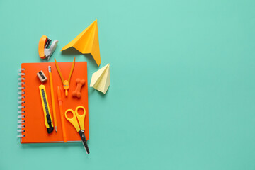 composition with stationery supplies and paper plane on turquoise background