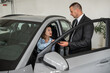 © RomanR - professional manager shows and taking  about car to female client in dealership