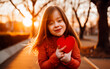 © henjon - Joyful girl with Down syndrome holding a red heart, in soft evening autumn light. shallow depth of field, Illustrative Generative AI