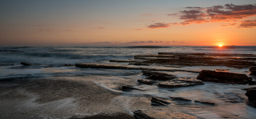 Wall Mural - Dramatic beautiful sunset on a rocky coast. Bright sun light on the horizon