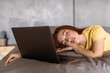 Young woman fallen asleep with her computer on the bed, exhausted from working late.