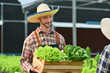 © Prathankarnpap - Image of friendly caucasian male gardener holding a wooden crate full of fresh organic vegetables, taking order from customer