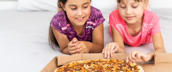 Two little girls eating pizza at home