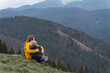 © somemeans - Mother and son rest and sit in an embrace on mountains background. Young mother with son sit on hillside