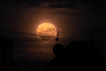 Wall Mural - Moon glowing in the night sky in front of a silhouette of a church