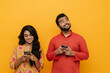 © Drobot Dean - Indian man and woman using mobile phones while standing isolated over yellow background
