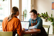 © Drobot Dean - Woman using laptop while training man with down syndrome to work in cafe