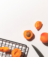 Organic ripe apricots under sun shadows on the white table top view