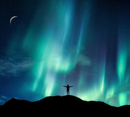 Wall Mural - aurora borealis glowing over silhouette hiker standing on the mountain in the night sky