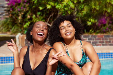 Wall Mural - Two Black friends laugh in the sunshine sitting at the pool, summer staycation