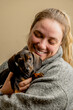 caucasian woman posing with her dachshund pet in her arms, woman smiling