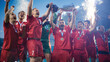 © Gorodenkoff - Football Finals Tournament Winning Team Celebrates Victory Cheering and Lifting Trophy Prize, Showing it to the Whole Stadium Arena. Happy Soccer Players Champions of International Championship Cup