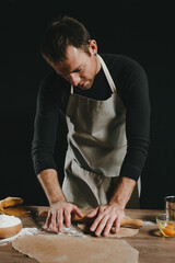 Wall Mural - Man rolling out the dough with a rolling pin on wooden background