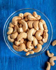 Wall Mural - Tasty cashew nuts in a bowl on a wooden table, top view.Bowl with cashew nuts on a wooden table, flat lay. 