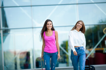 Two business women going on business trip carrying suitcases