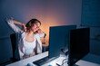 © Impact Photography - Woman stretching out at her desk while working late