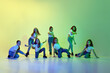 © master1305 - Group of little girls, children in casual clothes dancing, learning modern dance styles against green studio background in neon light. Childhood, hobby, sportive lifestyle, action and motion concept