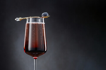 Kir Royal cocktail with blueberries wine glass on a dark gray background. Kir royal alcohol cocktail with copy space. Sparkling wine, liqueur, blueberry in a spoon. Shallow depth of field