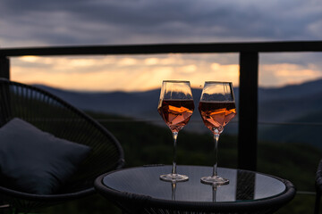 Two glasses of wine standing with a beautiful scenic mountain view. Mountain resort, enjoy moment