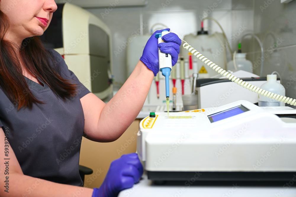 The laboratory female assistant puts a blood sample in biochemical ...