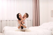 © New Africa - Happy woman and her daughter spending time together on bed at home, space for text. Mother's day celebration