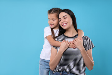 Canvas Print - Happy woman with her cute daughter on light blue background, space for text. Mother's day celebration